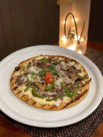 Fresh Grilled Flatbread topped with Shaved Beef, Green Peppers, Onions, Mushrooms & mozzarella