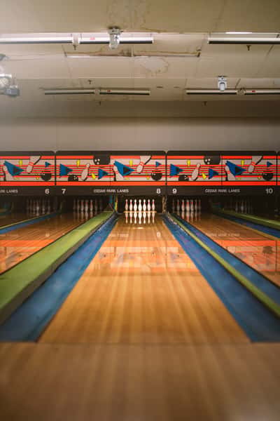 Colorful bowling lanes at Cedar Park Lanes with pins set up and bright geometric wall designs in the background.