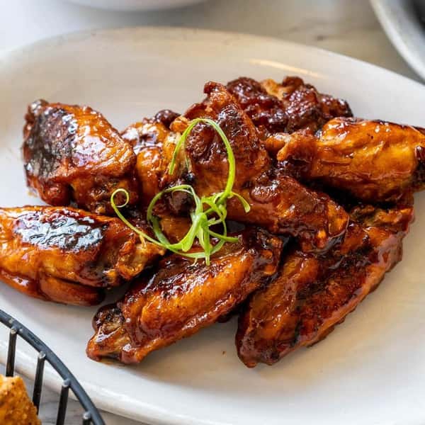 Glazed chicken wings garnished with sliced green onions