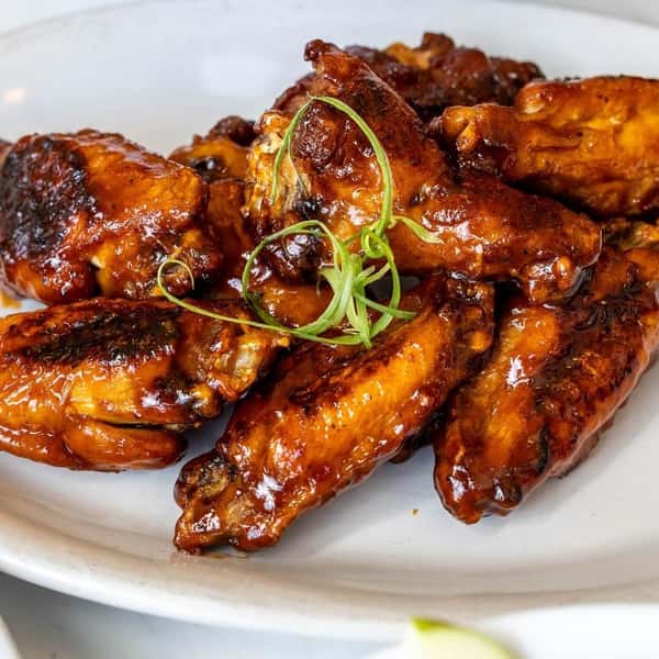 Close-up of glazed chicken wings garnished with green onions