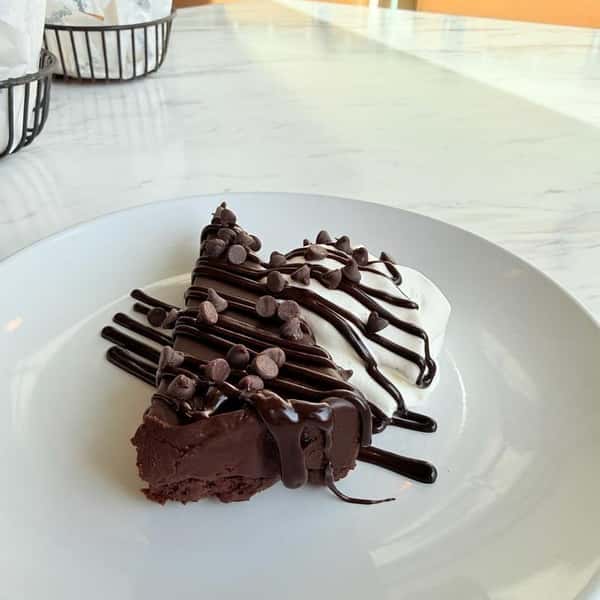 Chocolate brownie dessert drizzled with dark and white chocolate sauce