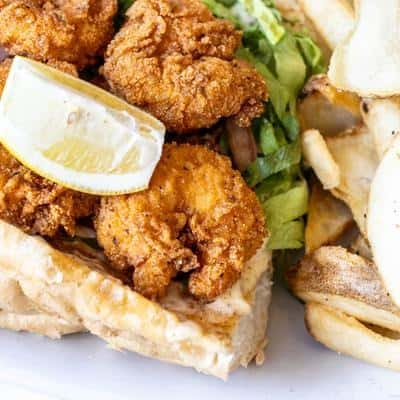 Crispy fried chicken served with a lemon wedge, fries, and greens