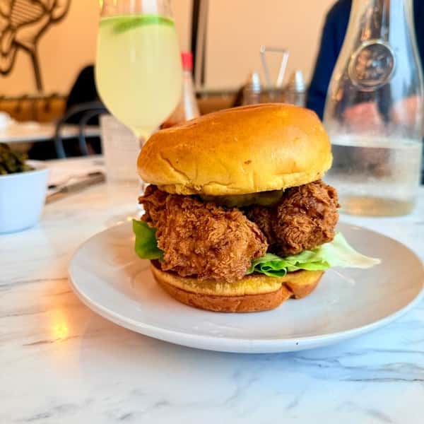 Fried chicken sandwich with lettuce on a toasted brioche bun, served on a white plate