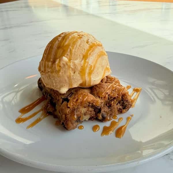 Warm baked dessert topped with a scoop of vanilla ice cream and caramel drizzle