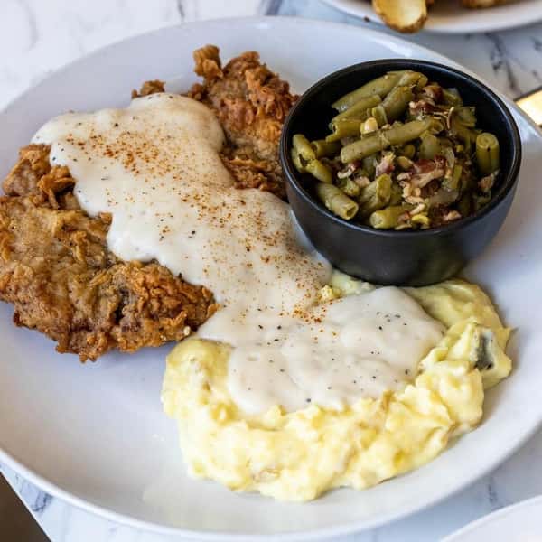 Chicken fried steak smothered in white gravy with mac and cheese and green beans