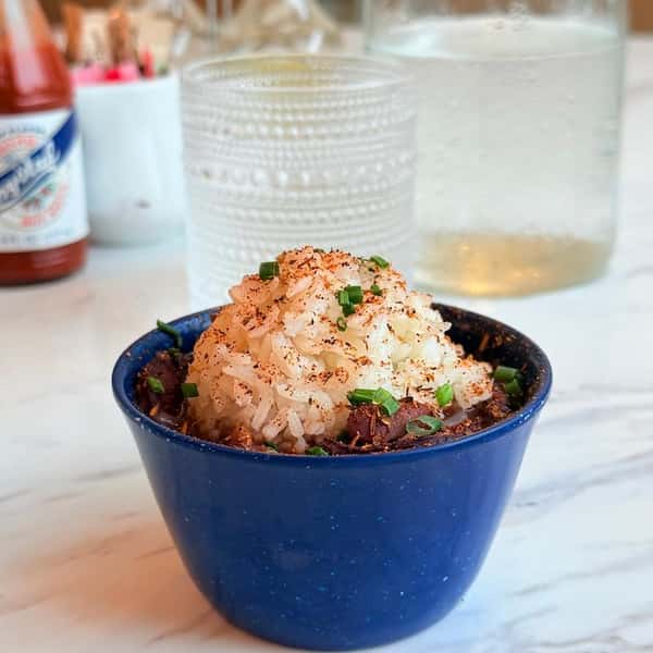 Blue bowl of gumbo topped with a scoop of rice and green onions