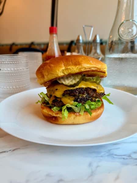 Double cheeseburger with melted cheese, lettuce, and pickles on a brioche bun
