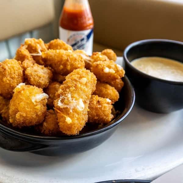 Crispy fried bites served with a creamy dipping sauce and hot sauce