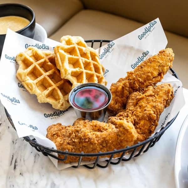 Chicken and waffles served in a basket with dipping sauces