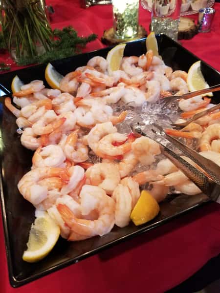 Assortment of Shrimp in a tray with sliced lemons with two tongs