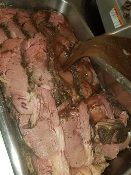 Slices of fresh meat in a tray with sauce being poured on top