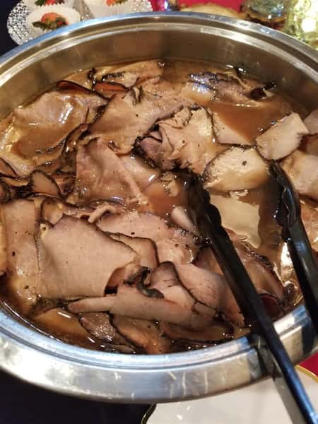Sliced Roast Beef in a pain with tongs