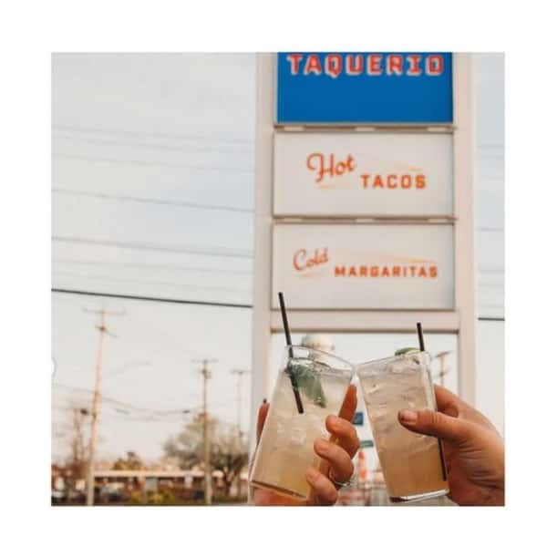 toasting margaritas with Taquerio sign in background