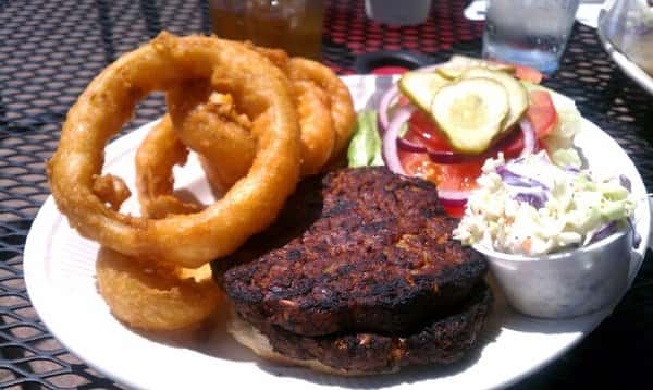 Open faced burger served with onion rings, side salad and slaw