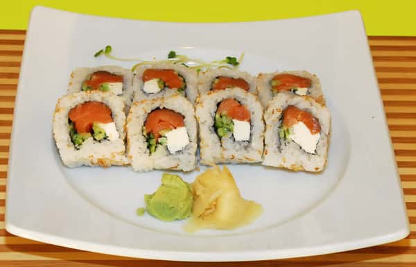 Sushi rolls with salmon, avocado, and cream cheese on a white plate.