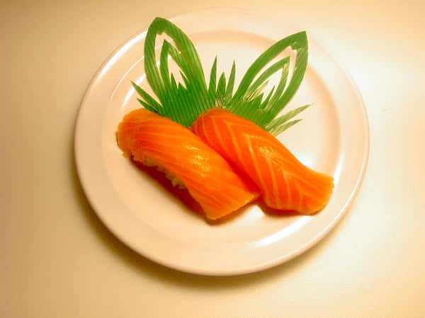 Two pieces of salmon nigiri sushi served with a garnish.