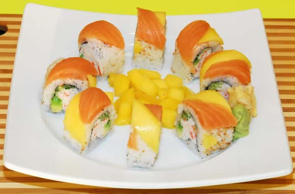 Sushi rolls topped with salmon and mango, served with mango cubes.