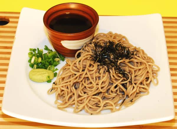 Cold soba noodles served with dipping sauce, scallions, and wasabi.