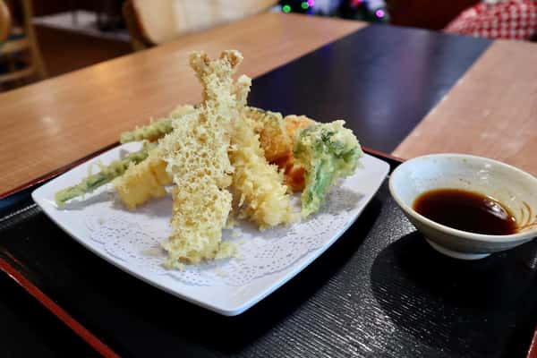 Plate of assorted vegetable and shrimp tempura served with a bowl of dipping sauce