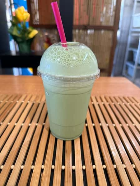 Iced matcha green tea latte in a plastic cup with a pink straw