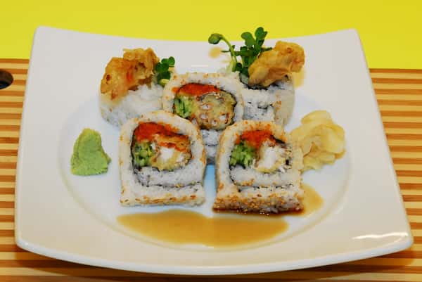 Sushi roll with cream cheese, avocado, and tempura flakes on a white plate