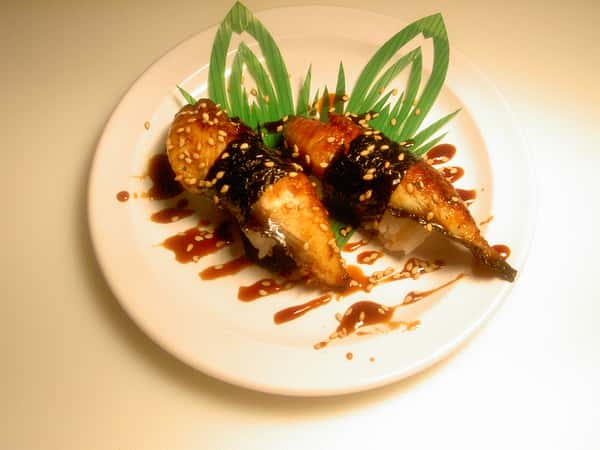Two pieces of eel sushi drizzled with sweet sauce and sprinkled with sesame seeds.