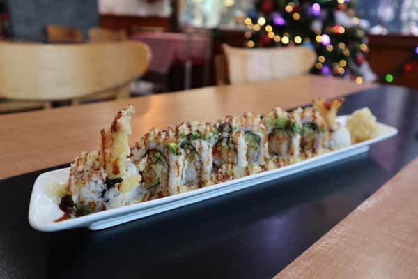 Sushi roll with tempura shrimp and sauce on top.