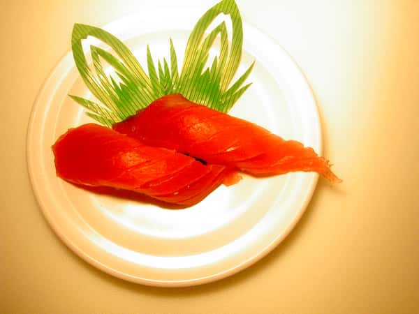 Two pieces of tuna nigiri sushi on a decorative plate.