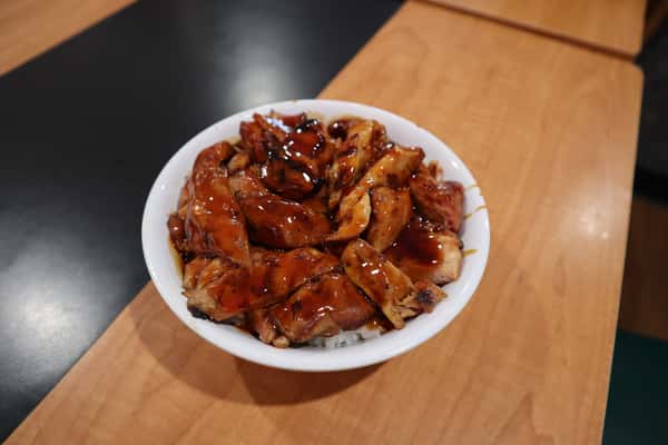 A bowl filled with grilled teriyaki chicken over steamed rice.