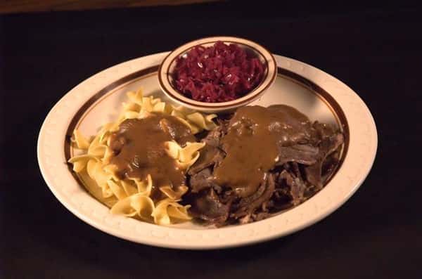 Pulled veal served with pasta and topped with brown gravy and a side of slaw
