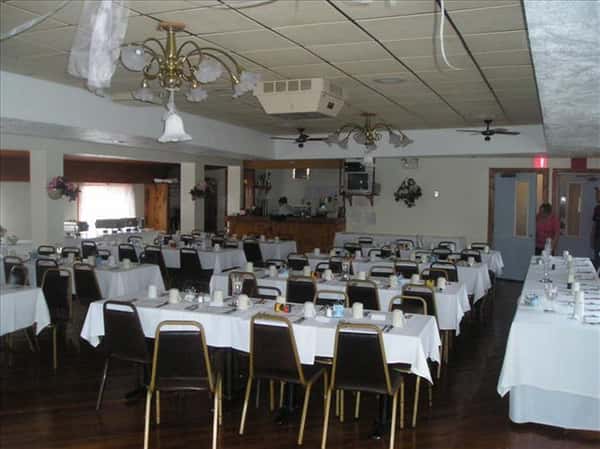 Dining hall with tables set in white linen and the bar in the background