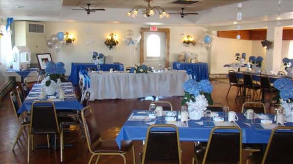 Private hall set for a special occasion with the tables decorated in blue linen and flowers