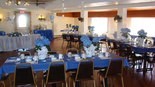 Private hall set for a special occasion with the tables decorated in blue linen and flowers