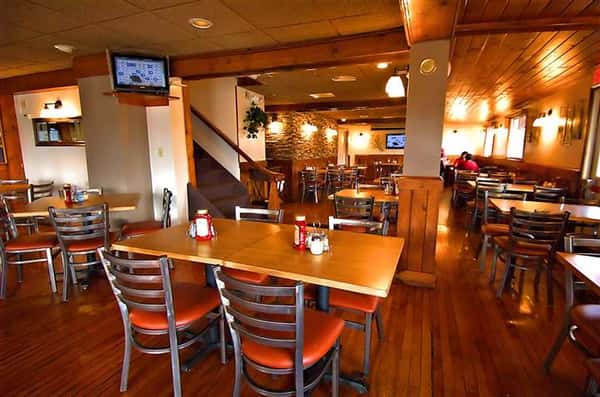 Interior shot of the dining hall with wooden floors and a wooden staircase in the background