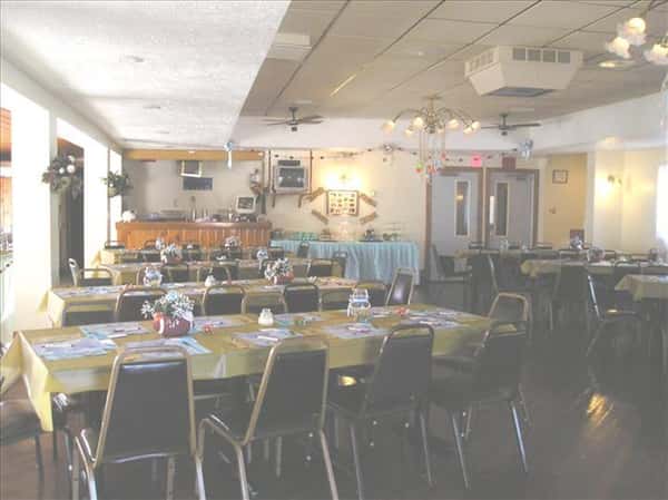 Event room set with tables in yellow linen and a buffet table at the back next to the entrance