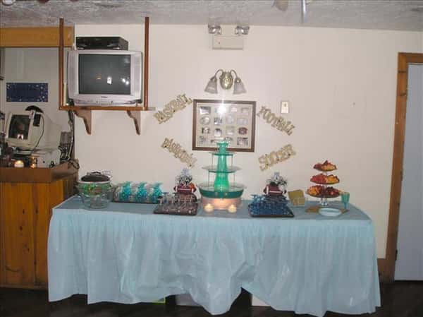Buffet table with blue linen set with cake stands and snack platter and glasses and drinks for a special event