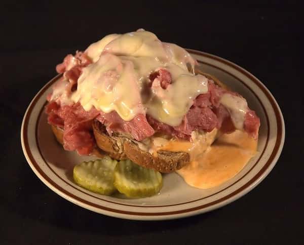 Open faced Reuben sandwich with thinly sliced corned beef, Russian dressing and Swiss cheese grilled on rye bread