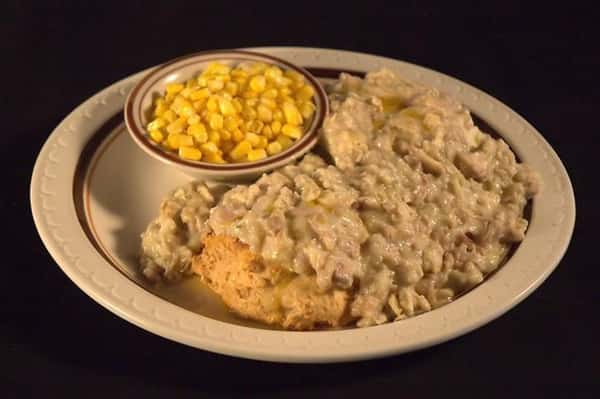 Fried fish fillet topped with sauce and served with a side of corn