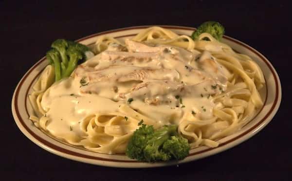 Fettuccine Alfredo topped with chicken strips and broccoli florets