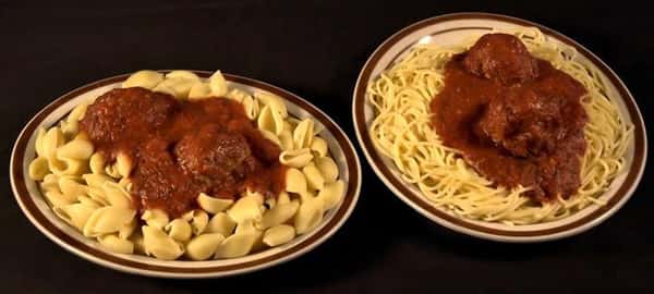 Two plates of pasta. A plate of shells and a plate of spaghetti both topped with two meatballs in marinara sauce