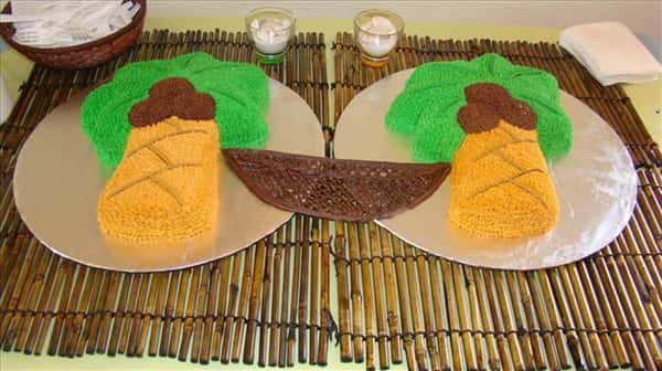 Special cake in the shape of two coconut trees and a rope hammock hanging between them set on bamboo place mats