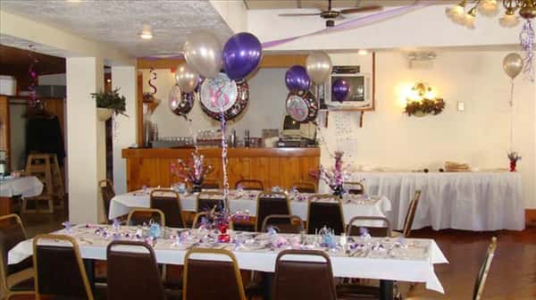 Private hall set for a special occasion with the tables decorated wprivate hall set for a special occasion with the tables decorated with white and purple balloons and flower centerpieces and a bar counter in the background