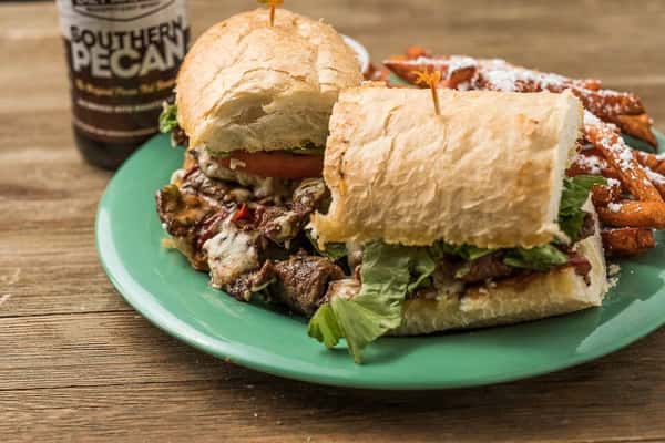 Steak sandwich with cheese, tomatoes and lettuce on a sandwich roll