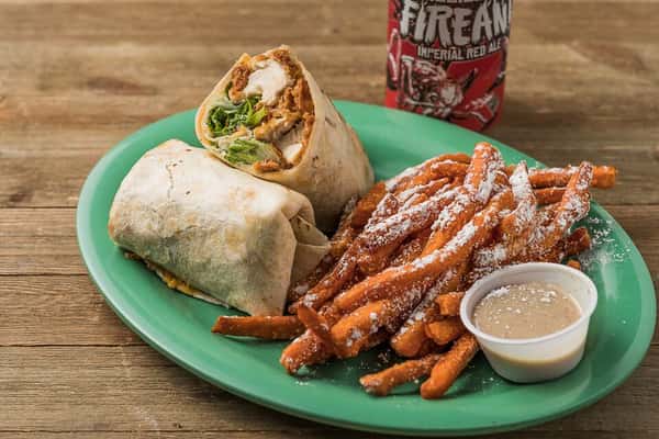 Crispy chicken and lettuce in a wrap with a side of sweet potato fries