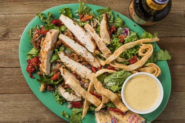 Grilled chicken, tortilla strips, cheese, sun dried tomatoes and a side of dressing on a bed of lettuce