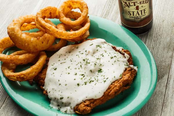 Fried chicken topped with white sauce and a side of onion rings