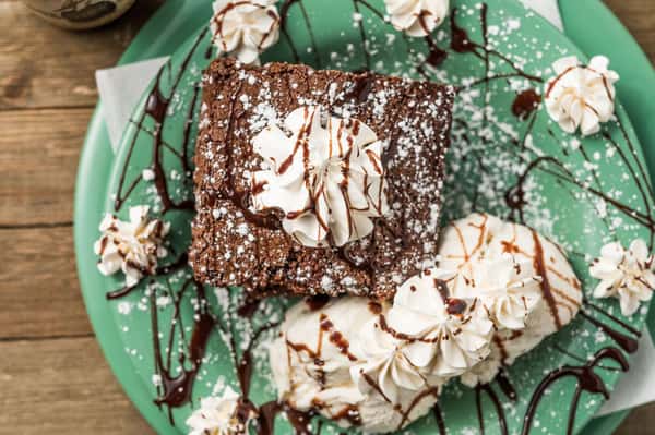Brownie topped with whipped cream and chocolate fudge