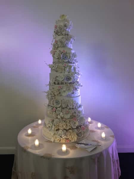 Tiered white wedding cake with flowers going down it
