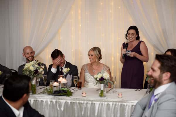 A bridesmaid giving a speech in front of the bride and groom