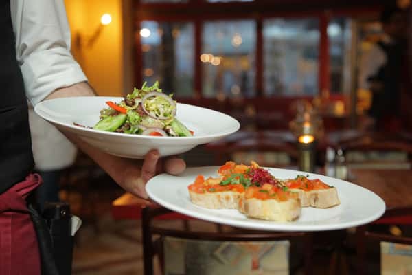 Waitress' hands holding two plates of food